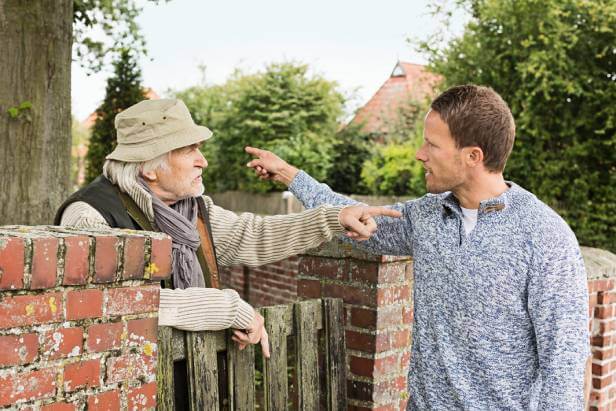A young and an old man arguing over a fence about a neighbor dispute.