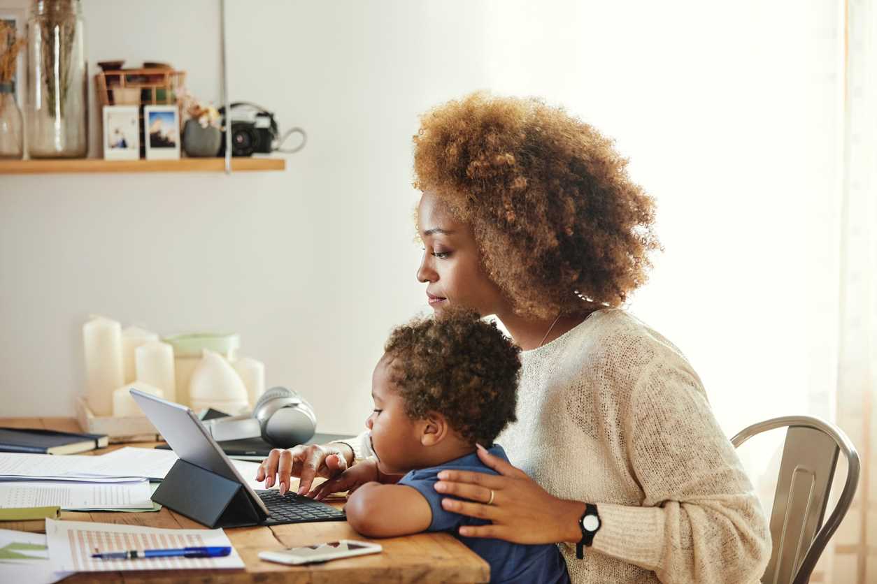 Woman holding toddler on her lap as she types