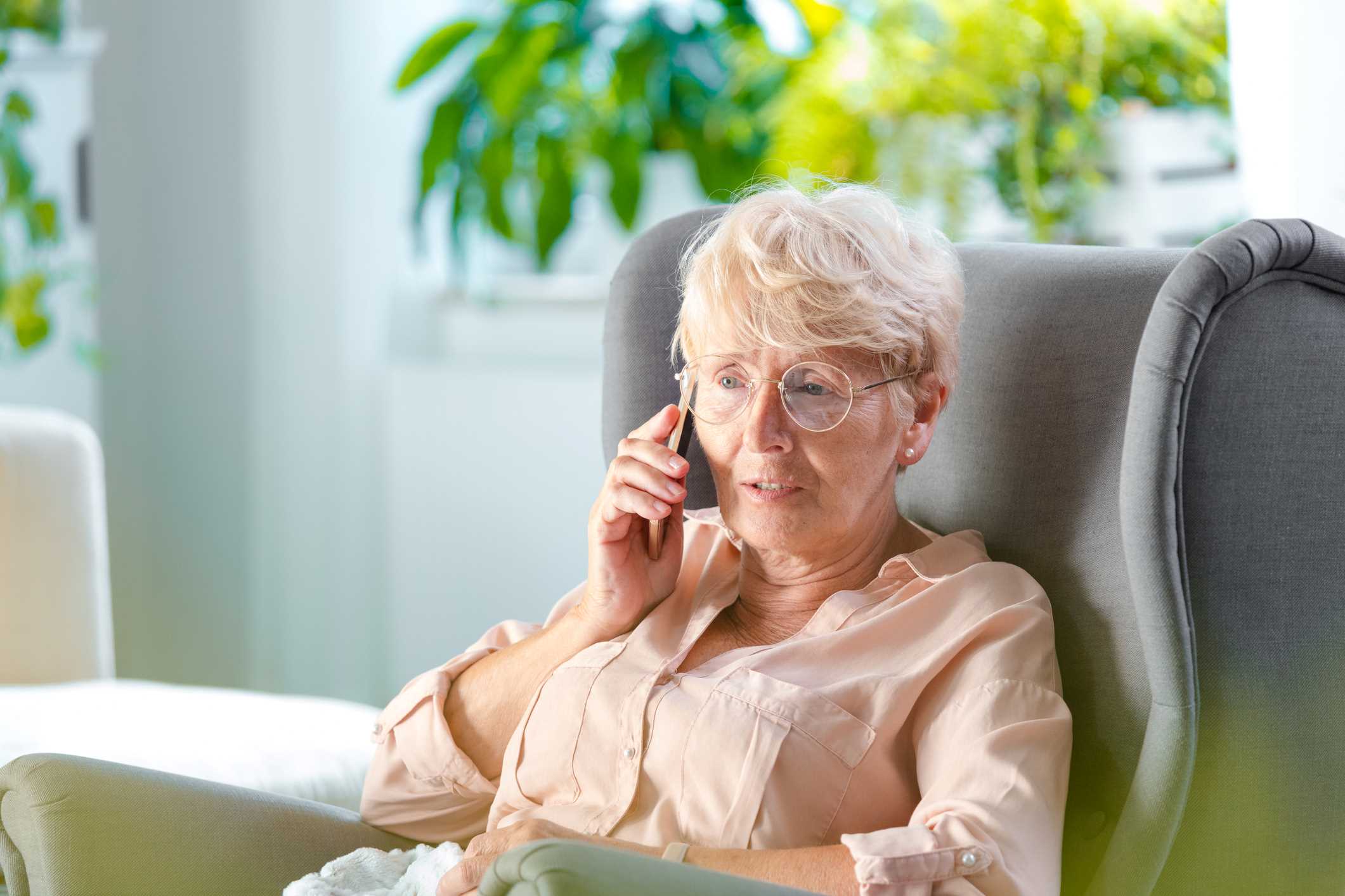 Elderly woman sitting in a comfortable chair and talking on a cell phone