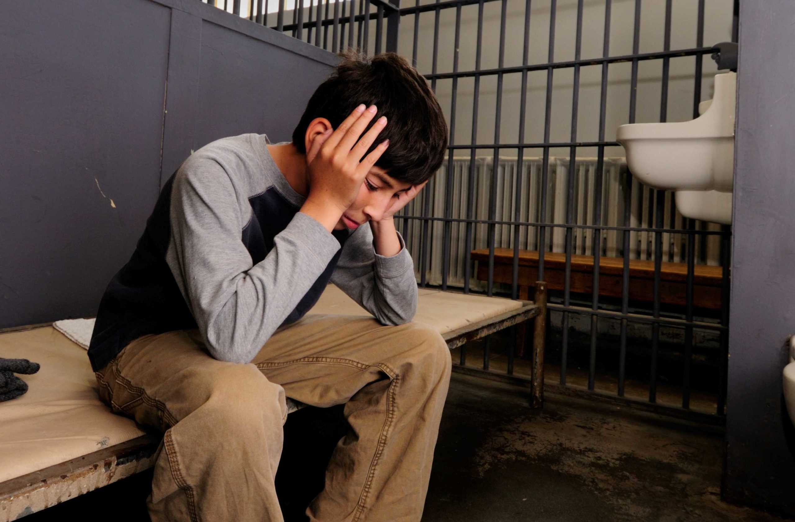 Adolescente sentado en una celda de la cárcel