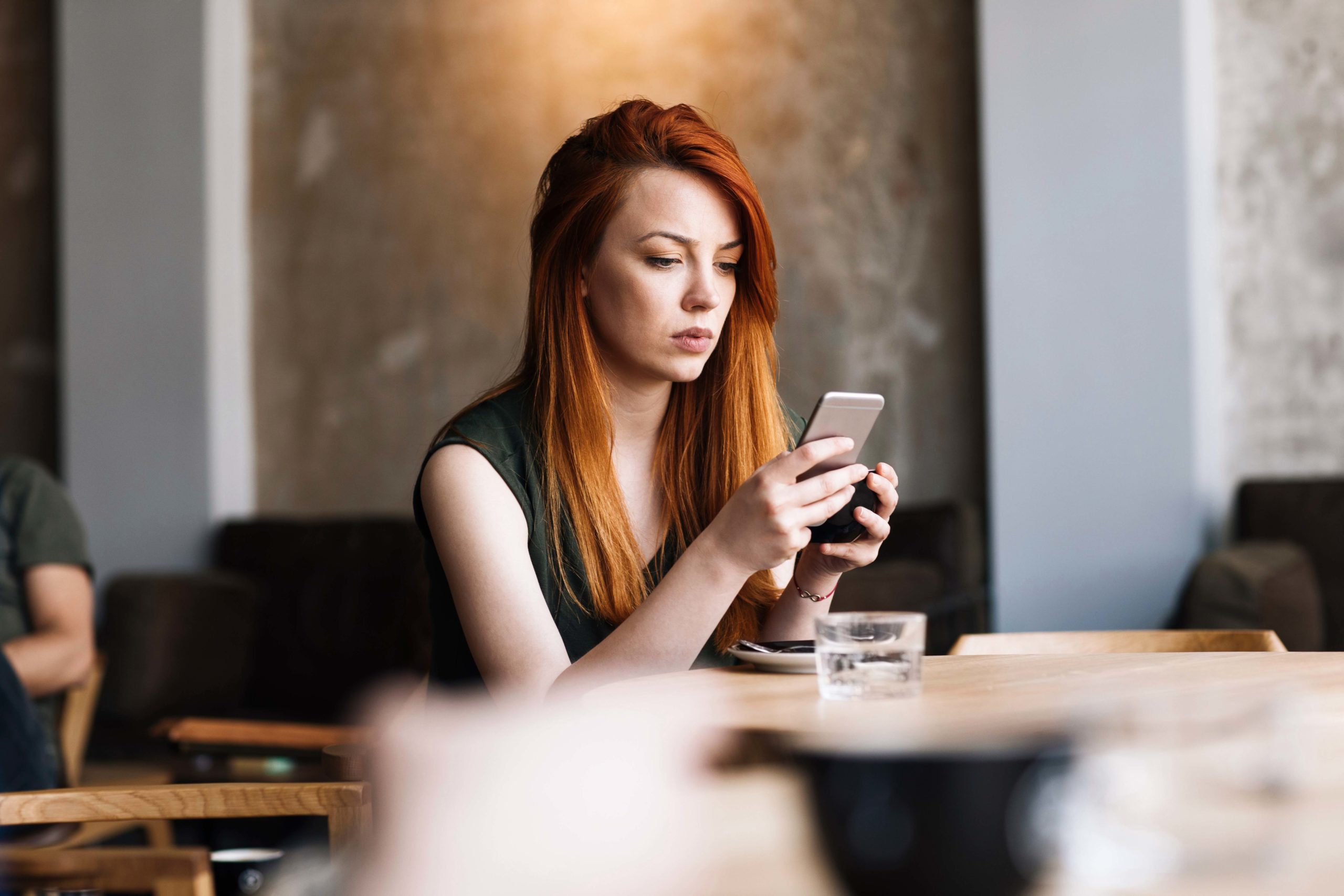 Mujer empleada mirando las redes sociales en su teléfono inteligente