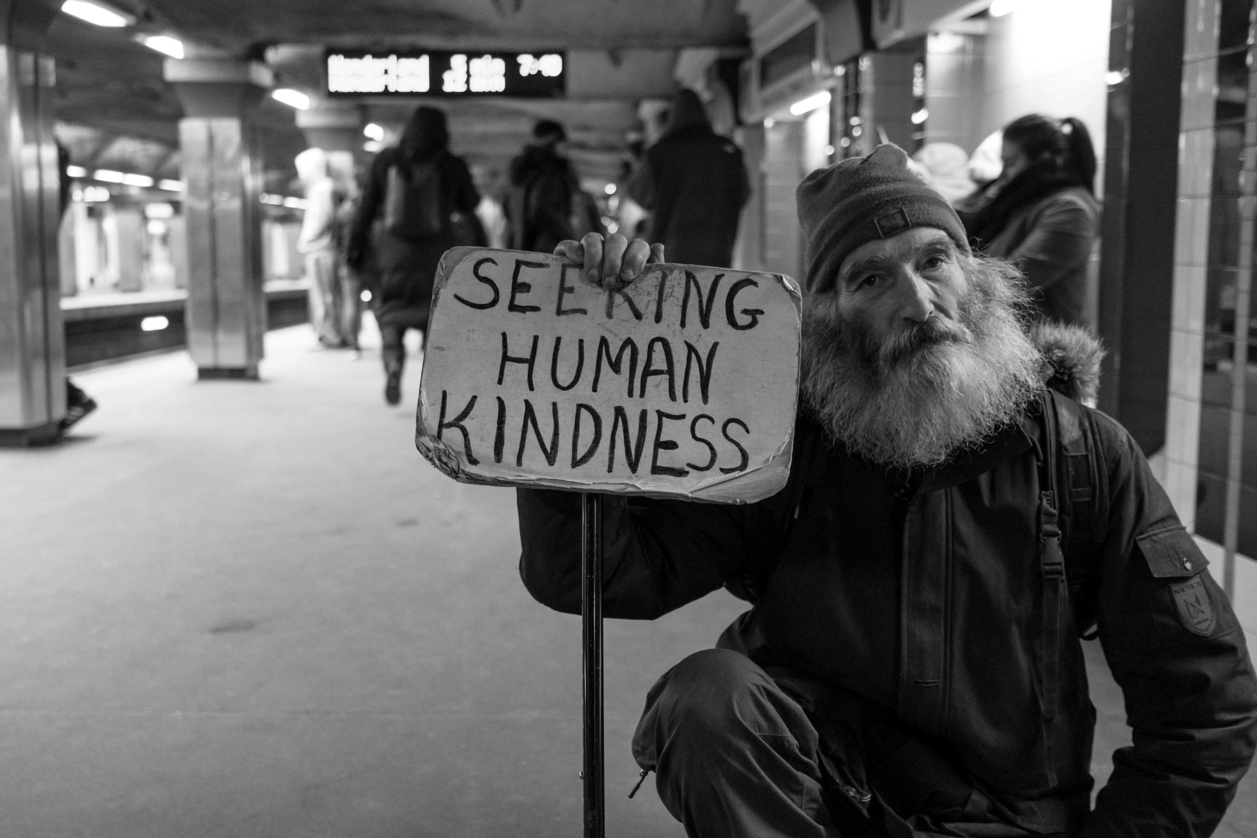 Hombre sin hogar con un cartel que busca la bondad humana