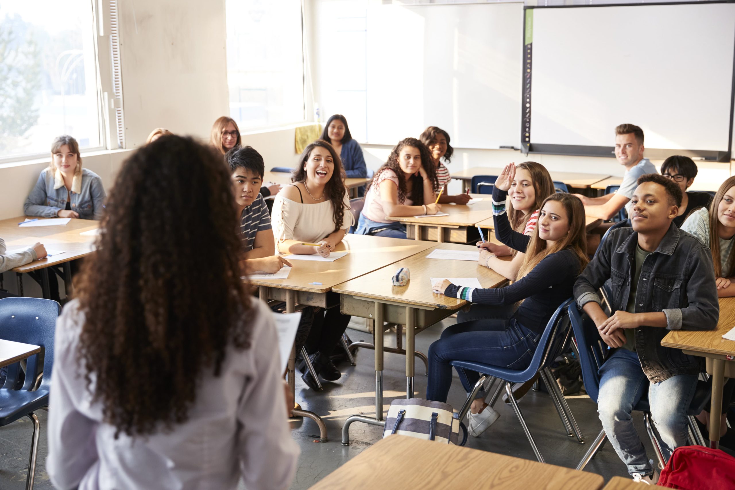 Estudiantes de secundaria escuchando a su maestro en un salón de clases