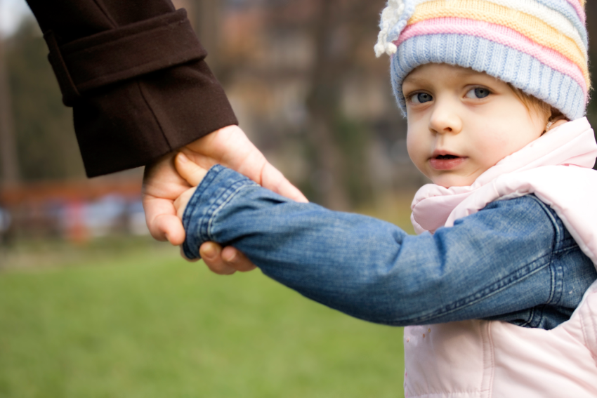 Young child holding hands with a caregiver