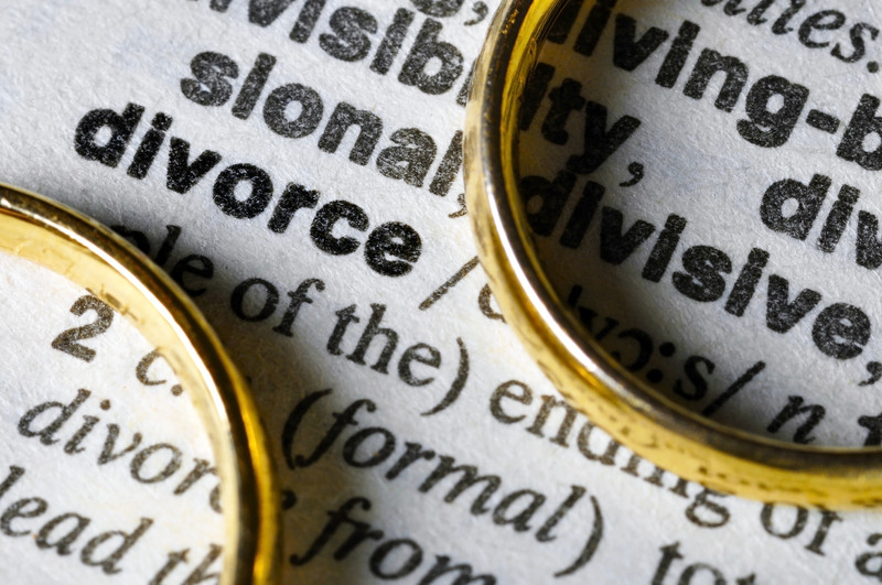 Definición de divorcio en un diccionario junto a 2 anillos de boda