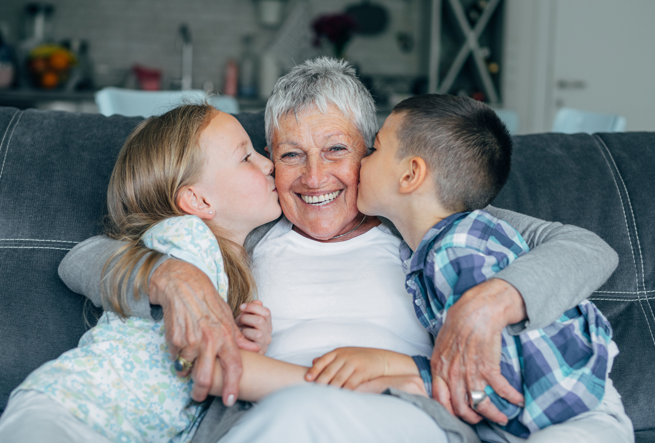Abuela recibiendo besos de sus 2 nietos