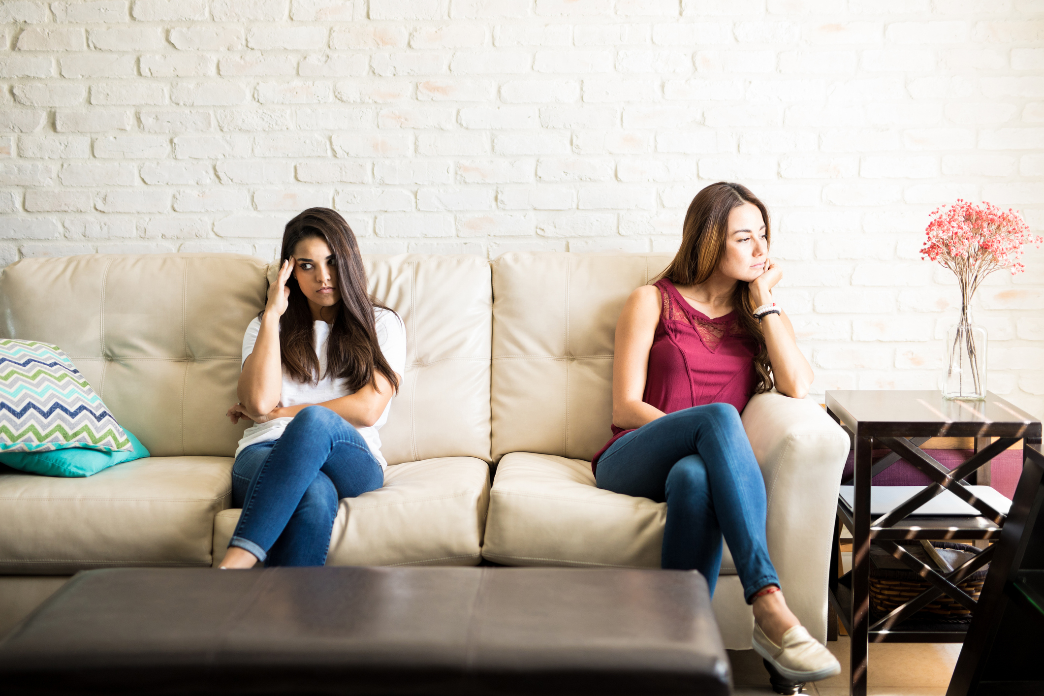 Unhappy roommates sitting on a couch but not talking