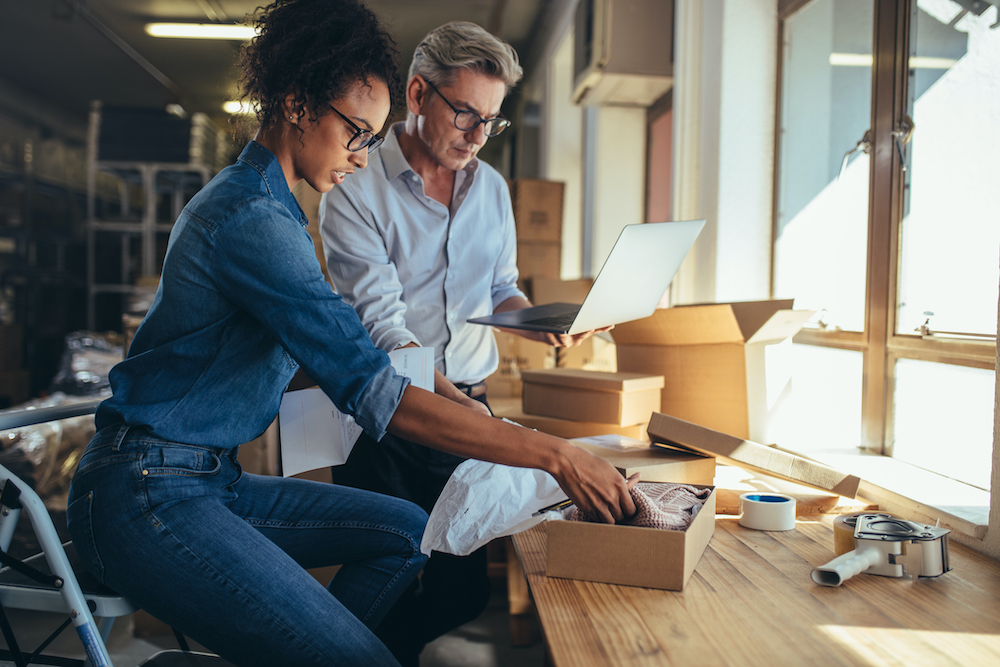 Man and woman small business owners packing boxes to ship