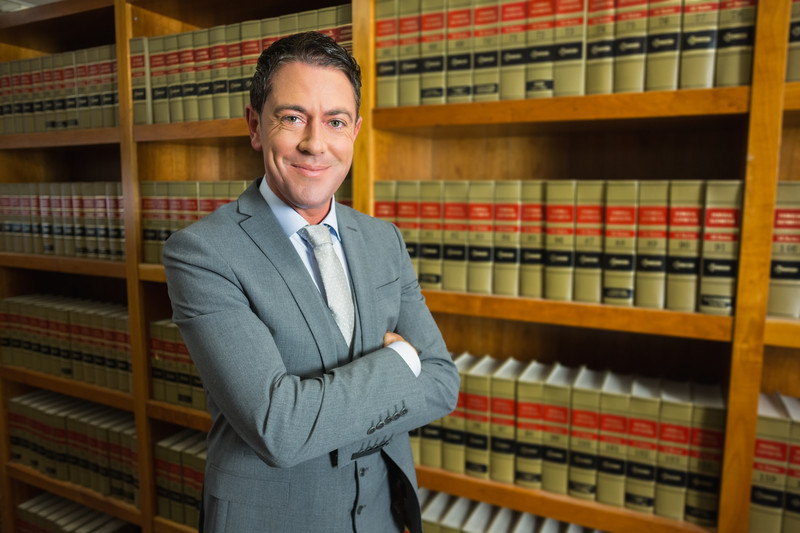 Lawyer standing next to bookshelf with legal books