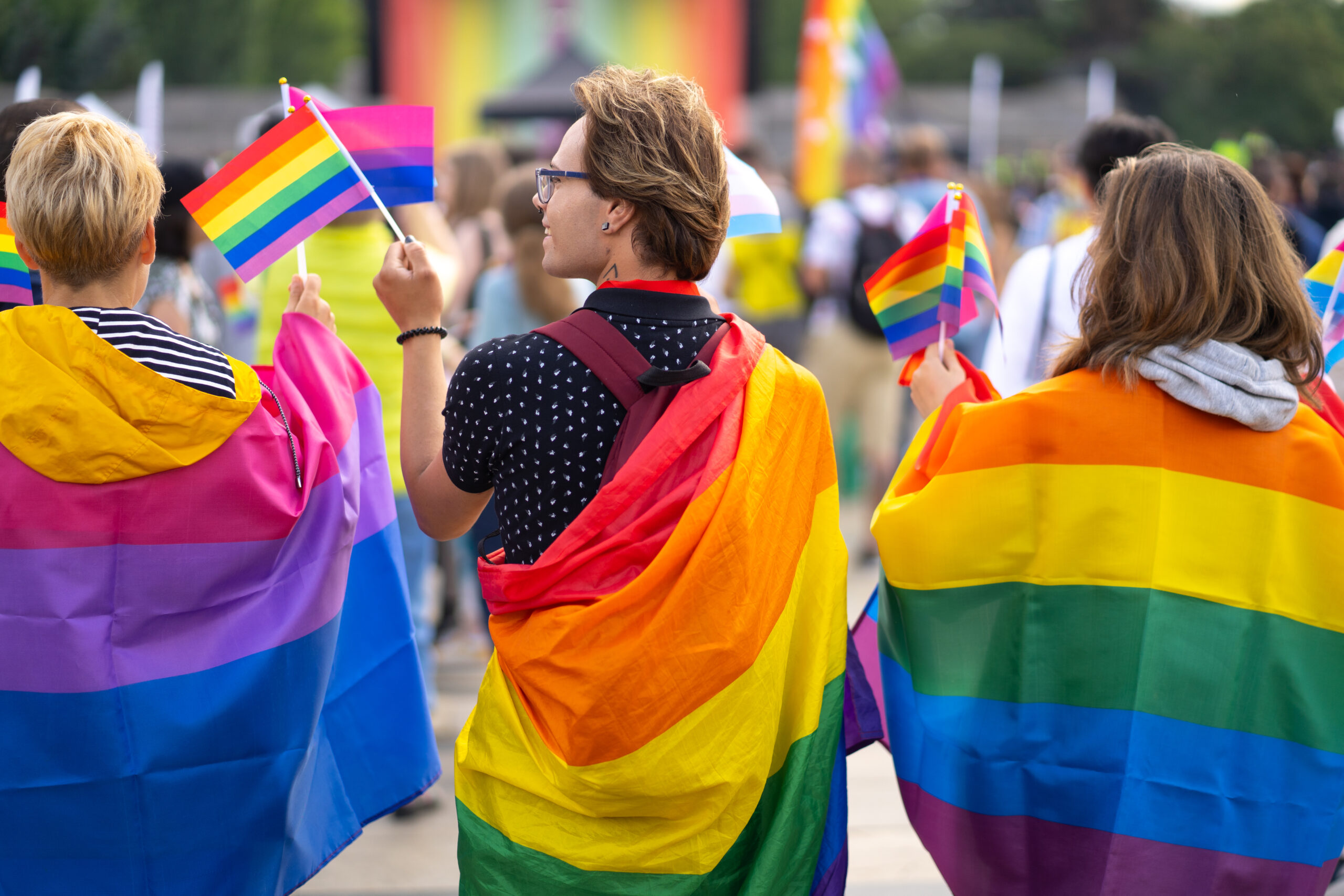 People wearing gay pride rainbow flags in street