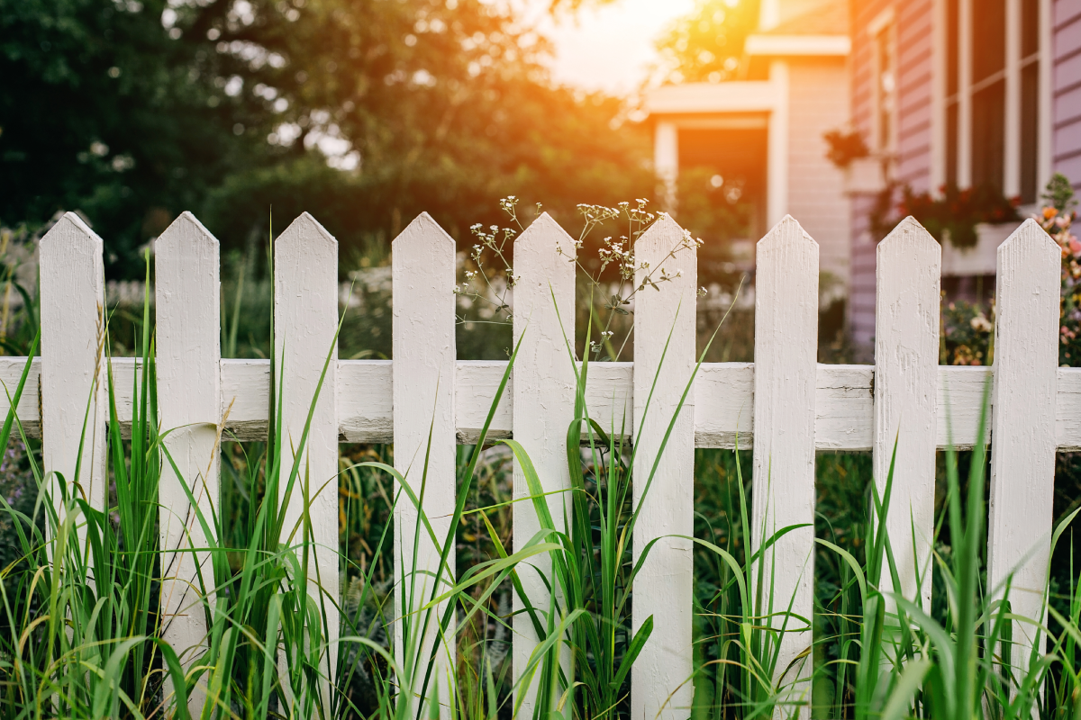 A white picket fence along a piece of real estate property.