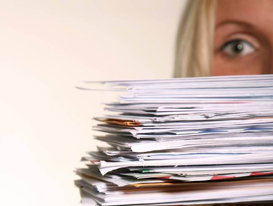 Woman holding a tall stack of student loan forgiveness paperwork.