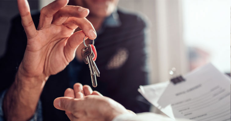 Real estate agent giving keys to a new renter or homeowner after signing documents.