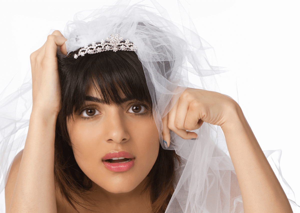 Bride-to-be wearing a veil wondering if she needs wedding insurance