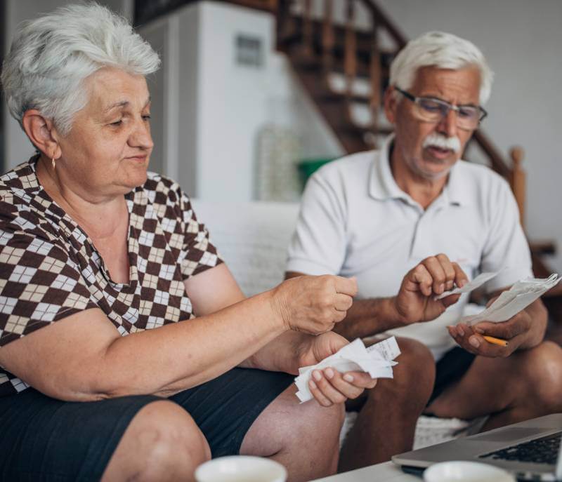 Elderly husband and wife reviewing receipts after being financially exploited.
