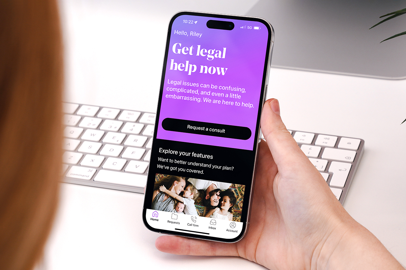 La aplicación LegalShield se muestra en la pantalla del teléfono de una mujer sentada frente a un teclado.